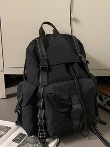 Mochila minimalista de nylon negro con múltiples bolsillos para estudiantes en entorno moderno