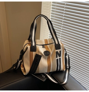 Detail of striped canvas fitness tote with removable shoulder strap on leather seat
