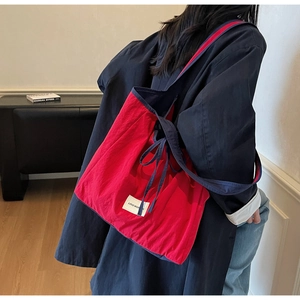 Detail of red and blue canvas tote bag showing the LOVE MORNING brand label and contrast trim