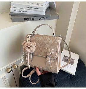 Detail of floral jacquard beige backpack with ribbon clasp and teddy bear charm