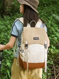 Outdoor color-block backpack with flap closure shown in a green forest hiking scene