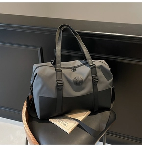 Detail of a large duffle bag in grey and black fabric on a textured black seat