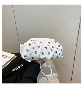 Dettaglio di pochette a pieghe bianca con borchie argento e texture in pelle litchi