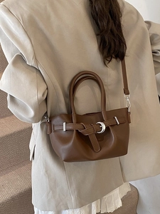 Sac seau plissé marron foncé avec boucle argentée porté sur un blazer décontracté