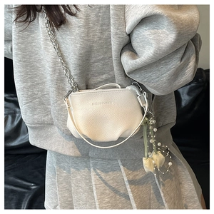 Détail du sac bandoulière blanc à motif litchi avec chaîne argentée et breloque perle