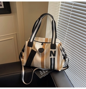 Macro detail of canvas stripe tote with circular logo patch and black fabric handle