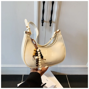 Detail of cream half-moon underarm bag featuring vintage wooden bead charm and PU leather