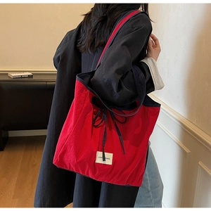 Detail of red canvas tote bag with contrast blue handles and decorative bow knot