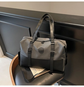 Detail of large travel duffel bag with grey canvas and black leather handles on a chair