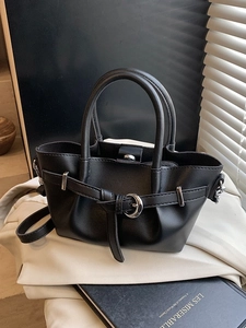 Sac seau plissé noir avec boucle argentée et poignées rondes sur tissu blanc doux