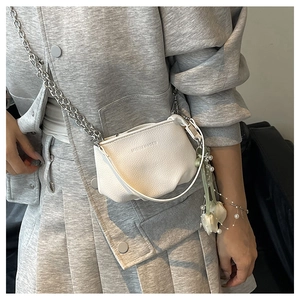 Détail du sac blanc en cuir grainé avec chaîne argentée et pendentif floral
