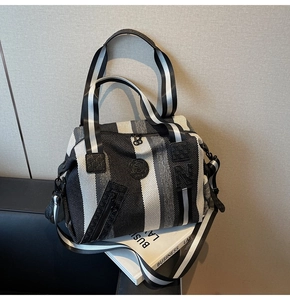Detailed close-up of striped woven large capacity shoulder bag with a logo and metal zippers