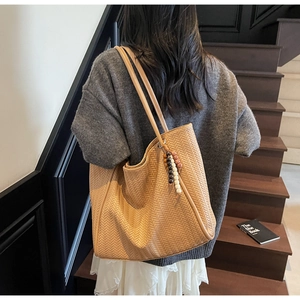 Detail of light brown woven tote bag featuring a chevron texture and colorful wooden beads