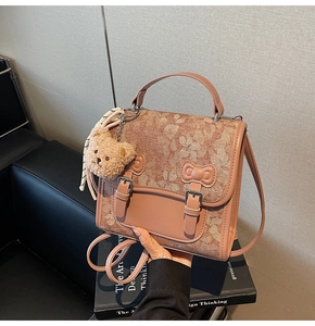 Detail of pink vintage messenger bag featuring floral lace texture and teddy bear charm