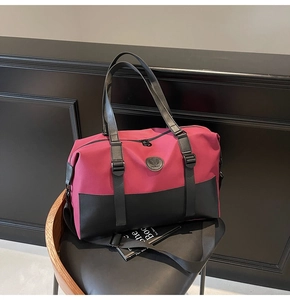 Close-up of burgundy and black luggage bag with adjustable strap on a leather chair