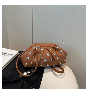 Dettaglio borsa a pieghe marrone con borchie in metallo argento e texture in ecopelle premium