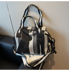 Detail of striped woven tote with front zipper and round N logo patch texture
