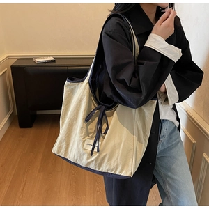 Detail view of a large two-tone nylon tote bag showing side drape and knot detail