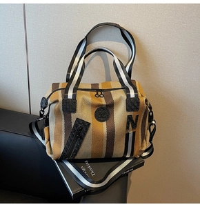 Detail of striped canvas gym tote with N applique, shoulder strap and Design Thinking book