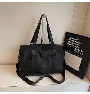Detail of black nylon travel bag with dual handles, crossbody strap and circular logo