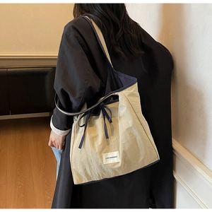 Detail of canvas tote bag showing LOVE MORNING label and contrasting blue bow tie strap