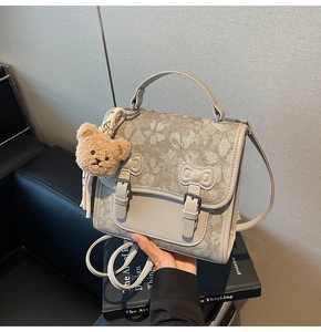 Detail of floral fabric backpack with leather trim, twin bows and a plush bear charm