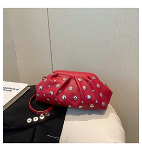 Dettaglio della pelle rossa con trama litchi e borchie argentate sulla borsa chic