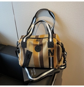 Close-up of striped canvas gym tote bag with woven handles and decorative zip pocket