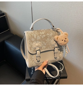 Detail of grey patterned backpack with flower prints and a cute teddy bear charm