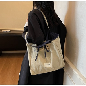 Detail of cream tote bag with blue trim and Love Morning label worn by a model