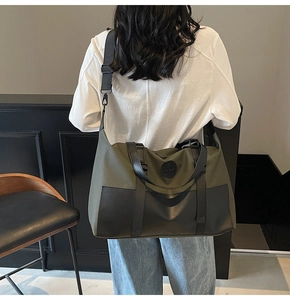 Close-up of olive green canvas travel bag with black leather details and logo