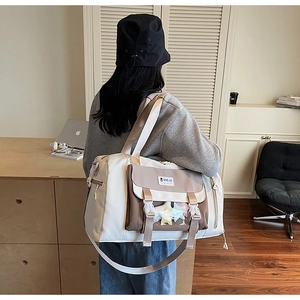 Borsa da viaggio vista laterale con tasca a fibbia, tracolla e finiture marroni