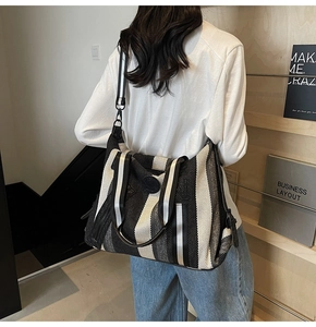 Detail showing high-capacity striped canvas tote bag with wide shoulder strap in lifestyle use