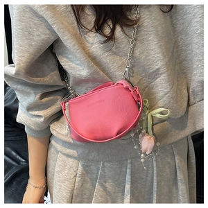 Gros plan du sac seau rose en cuir grainé avec chaîne argentée et breloque tulipe