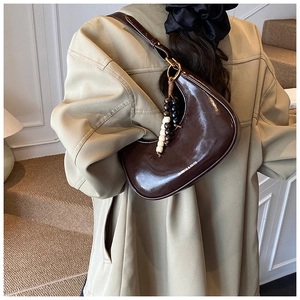 Brown patent leather hobo bag featuring a decorative wooden bead pendant and fashion logo