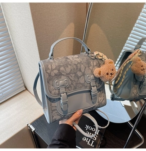 Detail of light blue floral backpack with double buckle closure and plush bear charm