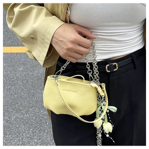 Détail du sac seau en cuir jaune clair avec chaîne argentée et breloque fleur perle