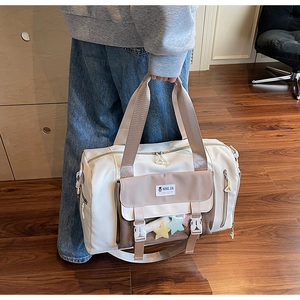 Dettaglio di una borsa da viaggio crema con cinghie marroni e ciondolo a stella
