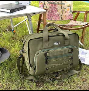 Detail of army green canvas travel bag with reinforced handles and adjustable strap on grass