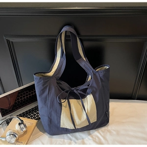 Detail of canvas tote bag showing navy and cream contrast design with bow ribbon tie