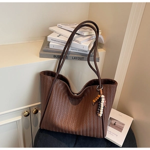 Close-up of brown woven tote bag with herringbone pattern and colorful wooden bead tassel