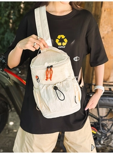 Detail der cremeweißen Nylon-Umhängetasche mit Faltenstruktur und orangefarbenem Zipper
