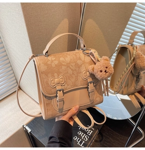 Detail of beige backpack with floral pattern, double buckles and a brown teddy bear charm