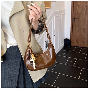Close-up of coffee brown hobo bag with vintage gold hardware and wooden bead pendant