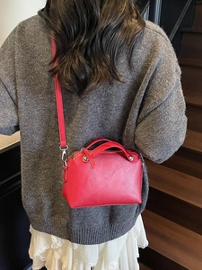Modische rote Lederhandtasche als Umhängetasche für Damen auf einer Treppe