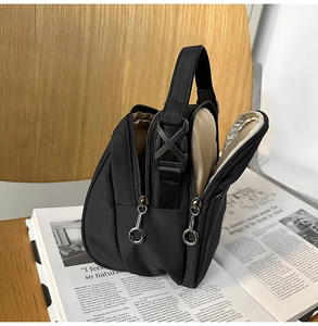 Detalle del bolso bandolera de nailon negro con compartimentos y asa de tejido