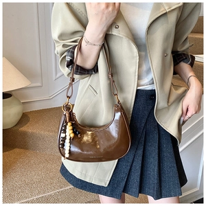 Brown patent leather half-moon bag featuring colorful wooden bead tassel charm detail
