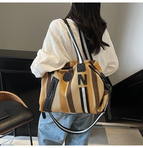Close-up of large striped canvas tote bag with black N leather patch and striped strap