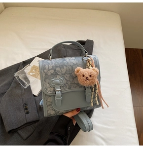 Close-up of light blue denim backpack with butterfly patterns and plush bear charm
