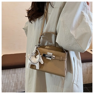 Detail view of camel crocodile pattern leather handbag with silver clasp and horse charm